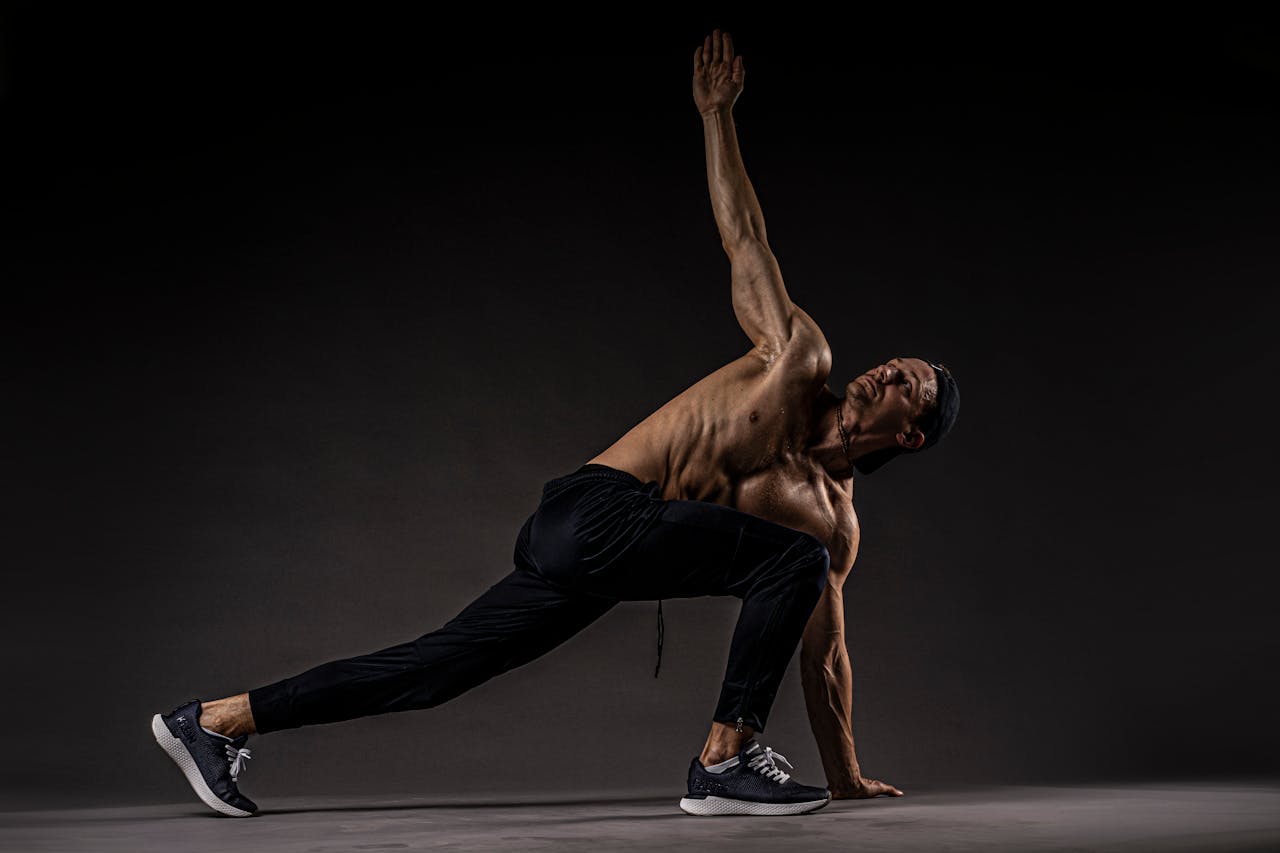 Shirtless man performing fitness stretch highlighting muscles and flexibility.
